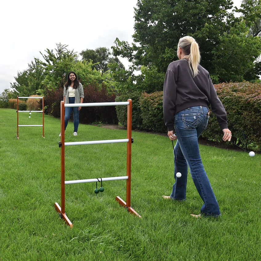 Twee vrouwen spelen laddergolf op een groen gazon met houten ladders en bolas